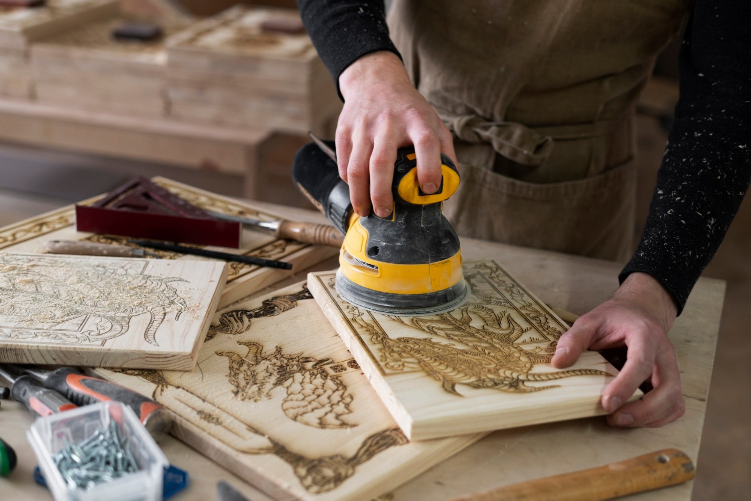 artisan ponçant une planche gravée chez ACDC Menuiserie à Montpellier, atelier de menuiserie bois,