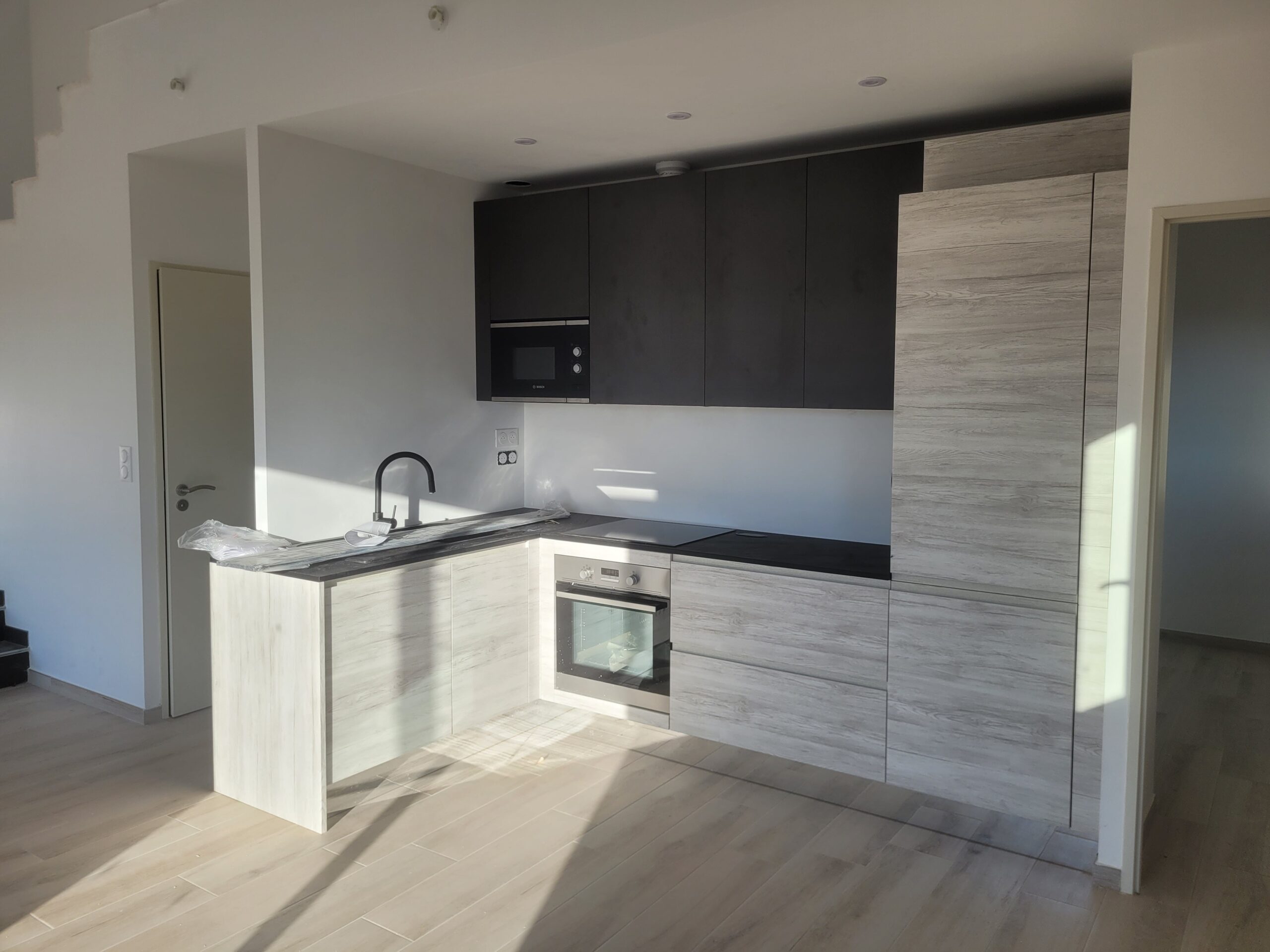 Cuisine moderne compacte signée ACDC Menuiserie à Montpellier, meubles bois vieilli et finitions noires élégantes,